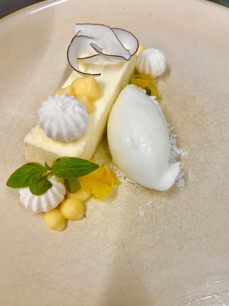 A white plated dessert with a quenelle of sorbet, meringue drops and citrus gel.